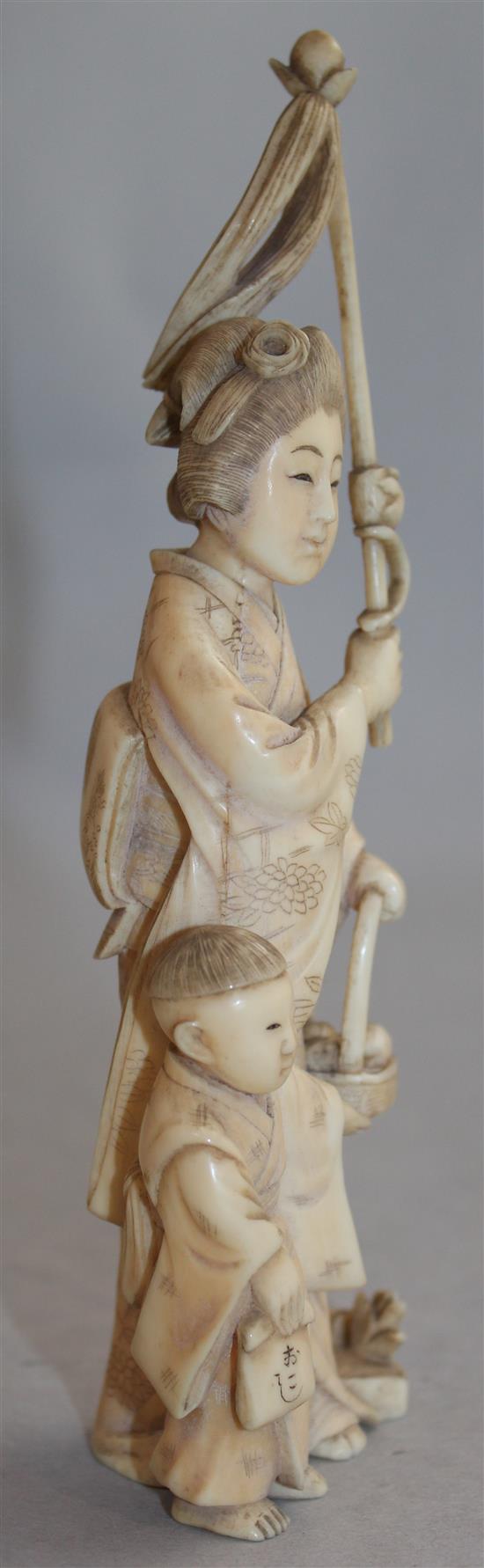 A Japanese ivory group of a woman carrying a basket of pomegranates, Meiji period, 16.8cm